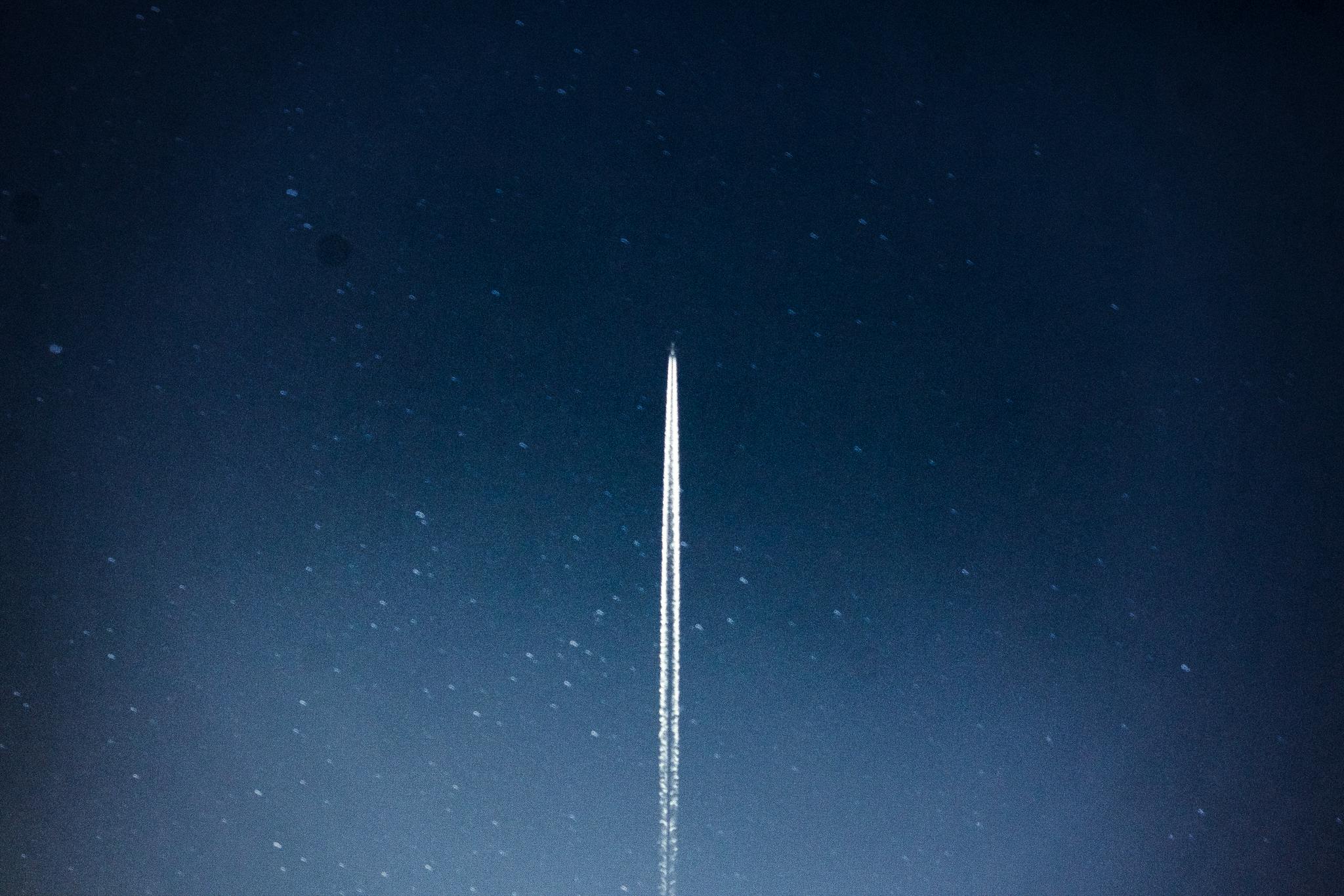 A rocket streaks through a starry night, leaving a trail in outer space.