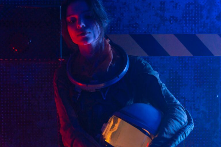 A woman astronaut in a spacesuit under vibrant red and blue lighting, evoking a futuristic, sci-fi atmosphere.